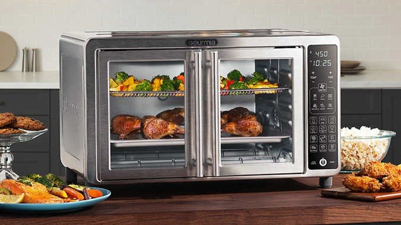 A modern stainless steel Gourmia Digital Air Fryer Oven with French doors, featuring a digital control panel, cooking crispy chicken and vegetables on multiple racks in a stylish kitchen setting. This image represents How to Use Gourmia Digital Air Fryer Oven for preparing delicious and healthy meals.